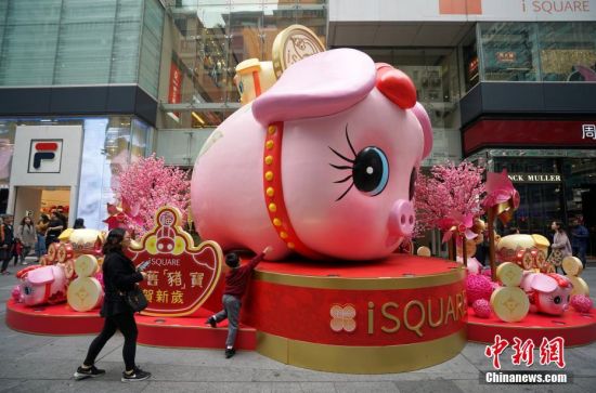 1月10日，随着己亥猪年临近，香港街头新春气氛渐浓，在车水马龙的尖沙咀闹市，商家提前搭好了猪年贺岁装置，一个个萌态可掬的“猪宝宝”吸引众多行人驻足观看拍照。中新社记者