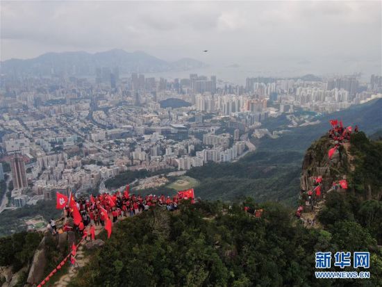 9月14日早上，有百余名香港市民分两批爬上狮子山顶，他们身穿红色T恤，挥舞国旗、区旗，并展示“庆祝中华人民共和国成立70周年”和“止暴制乱，恢复秩序”的横幅。图为市民抵达狮子山顶挥舞国旗、区旗。新华社记者