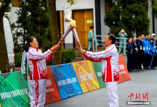 10月16日，火炬手章进与火炬手张文秀（左）在进行火炬接力。当日，第七届世界军人运动会火炬传递活动最后一站在武汉东湖绿道举行。中新社记者