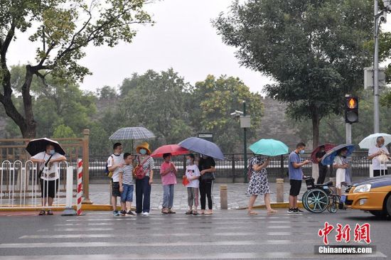 图为北京景山前街，民众冒雨出行。中新网记者