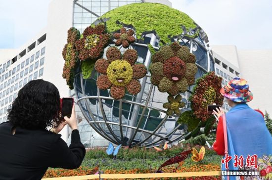 9月26日，市民在北京西单路口西北角《命运共同体》国庆主题花坛前拍照。
