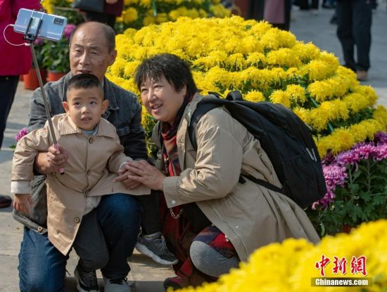 10月25日，市民在北京天坛公园菊花展上合影。中新社记者
