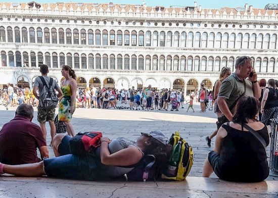 游客躺在威尼斯圣马可广场廊下休息。