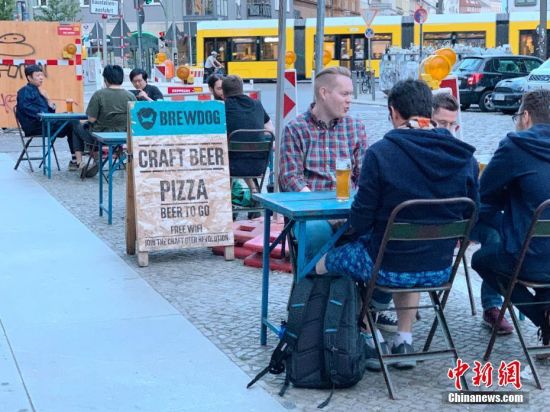 6月3日，柏林市中心一家精酿啤酒吧的顾客坐在街边饮酒。每桌顾客均保持了1.5米以上的距离。