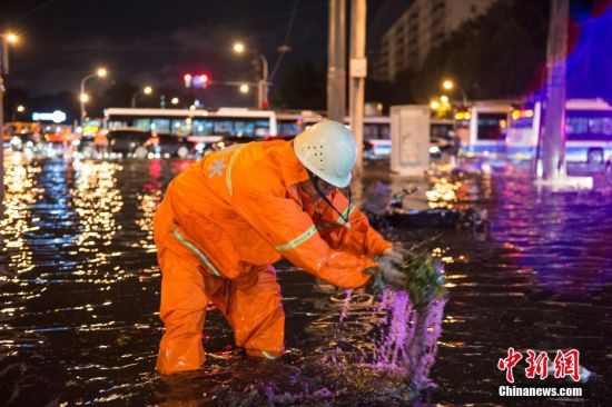 8月9日晚，北京市政工作人员清理堵塞的下水口。中新社记者