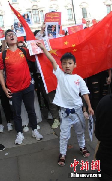 8月17日，旅居英国的华人华侨、中国留学生300多人自发聚集在伦敦市中心特拉法加广场、议会广场，与“乱港分子”组织的示威游行队伍对峙。人们挥舞中国国旗，高唱中国国歌，高喊“爱中国、爱香港”“反暴力、救香港”口号，声浪阵阵压过“乱港分子”阵营。图为自发聚集的华人队伍中，挥动五星红旗的6岁儿童。中新社记者